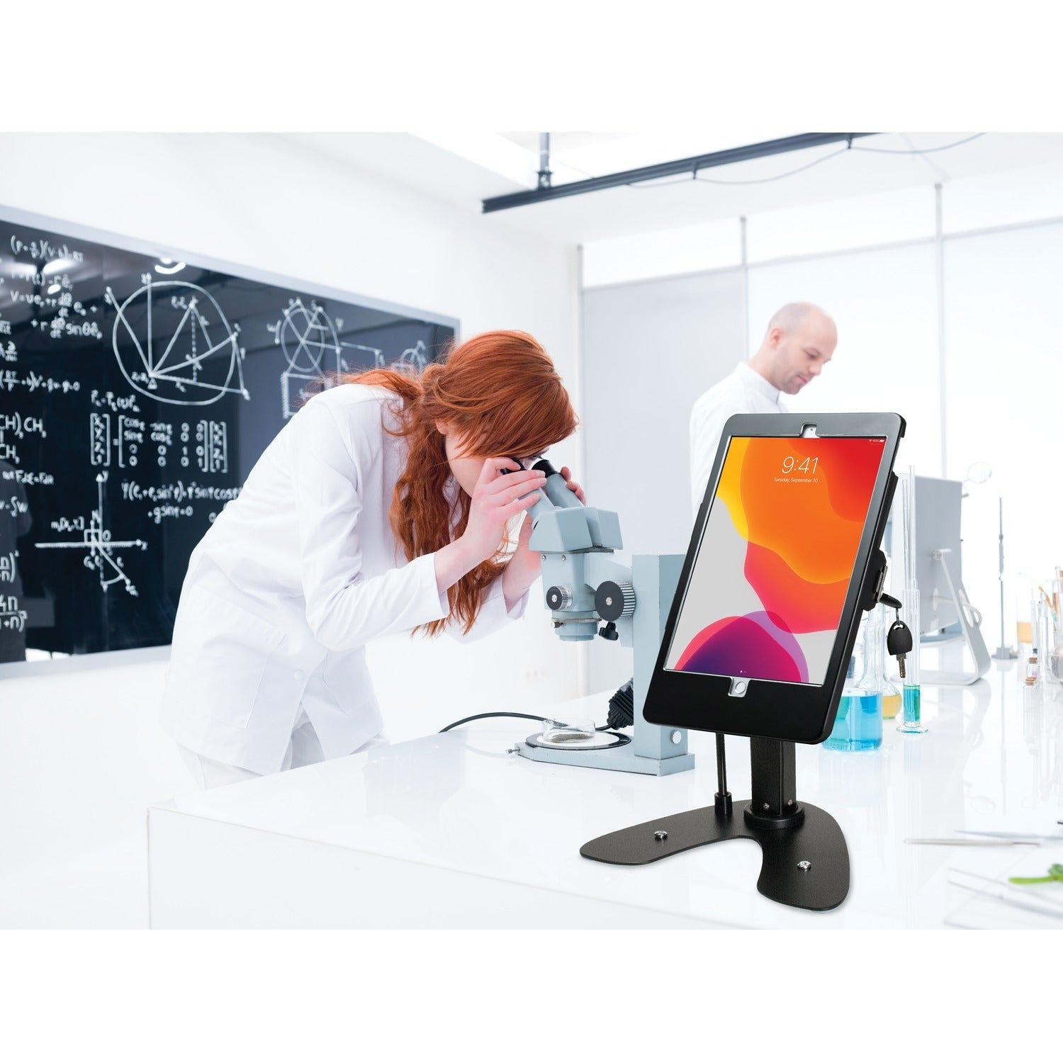 Female scientist using a 10.2-inch iPad on a CTA Digital kiosk stand in a laboratory setting.